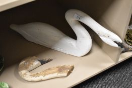 A carved and painted wooden swan ornament, of slender form and sold together with a similar swan