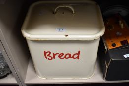 A vintage 1950s cream enamel bread bin with red writing and handles.