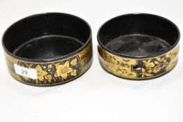 Two early 19th Century lacquered papier mache bottle coasters, decorated with gilt floral sprays