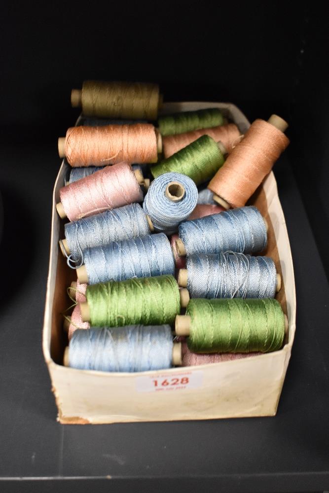 A box of embroidery threads on reels in mainly blue, green and pink.