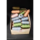 A box of embroidery threads on reels in mainly blue, green and pink.