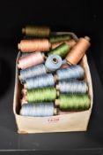 A box of embroidery threads on reels in mainly blue, green and pink.