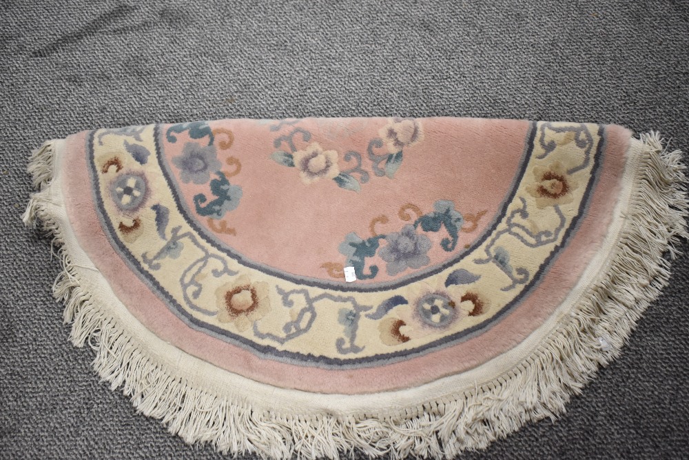 A traditional Chinese rug, in pink, grey and green tones, having fringed edge.