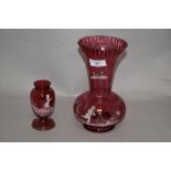 Two Mary Gregory style cranberry glass vases, the largest having a flared and crimped rim, measuring