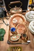 A copper kettle and an assortment of copper chargers, a trivet and a pin dish having enamel