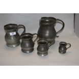 An assorted group of five antique pewter graduated measures