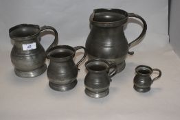 An assorted group of five antique pewter graduated measures