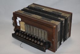 A 19th Century square concertina accordion, bearing a faded paper manufacturer's label, 26cm wide