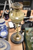 A late 19th century embossed brass oil lamp, having twist stem and wooden base, void of chimney.