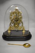 A late 19th Century brass single fusee skeleton clock timepiece, displayed under a glass dome,