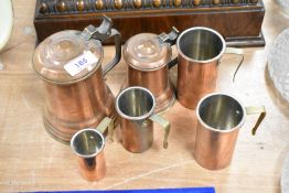 Four vintage copper and brass measures and two tankards.