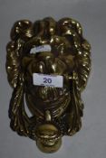 A 19th/20th Century cast metal door knocker in the form of a lion's head, measuring 18cm