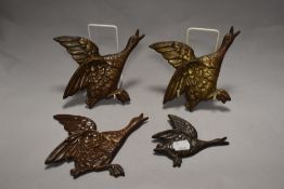 A group of four graduating cast metal flying geese ornaments, the largest measuring 19cm long