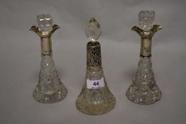 Three Edwardian cut glass lidded scent bottles, with silver and white metal collars, the largest
