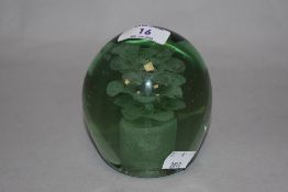 A Victorian green glass dump paperweight with encased sulphide veiled flower, and measuring 10cm