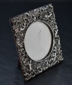 A late Victorian silver-mounted photograph frame, of square form with pierced and embossed C-scroll,