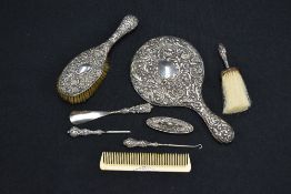 An Edwardian silver backed hand mirror, of traditional design embossed with foliate scrolls and