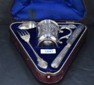 A Victorian cased silver christening set, comprising mug, spoon, fork and silver handled (metal