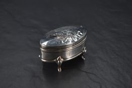 An Edwardian silver ring box, of hinged elliptical form, the cover embossed with cherubs and opening