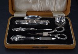 A George V silver mounted and cased manicure set, with embossed foliate decoration to the mounts,