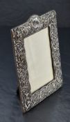 A late Victorian silver-mounted photograph frame, of shaped rectangular form embossed and pierced