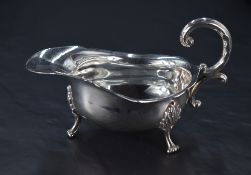 A George V silver sauce boat, of traditional design with scrolled handle, shaped rim and generous