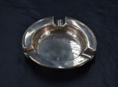 A George V silver ashtray, of circular form with moulded egg-and-dart edge detail, three moulded
