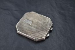A George VI silver powder compact of canted and hinged square form with engine-turned decoration