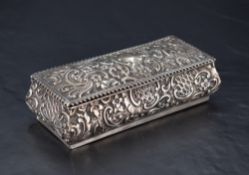 A late Victorian silver dressing table box, of hinged oblong form and embossed throughout with