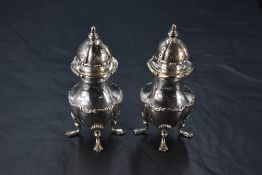 A pair of Edwardian cased silver pepperettes, of lobed urn-form, the domed, finial topped and
