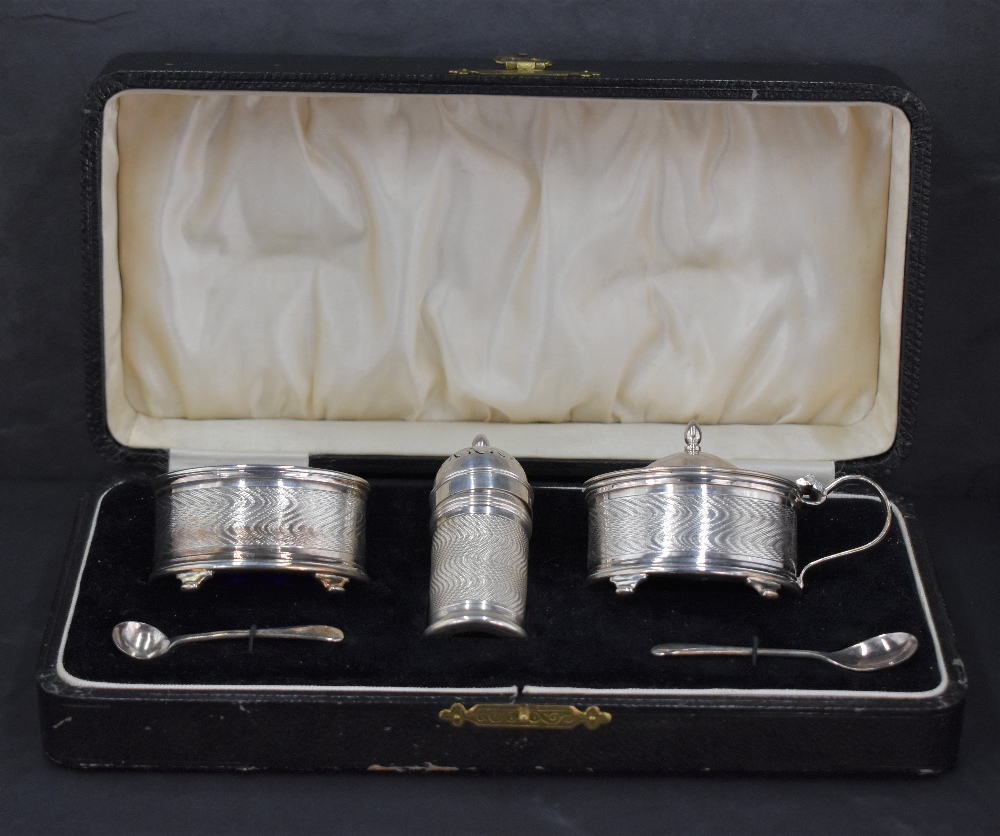 A George V cased silver condiment set, comprising pepperette, mustard and salt, each having engine-