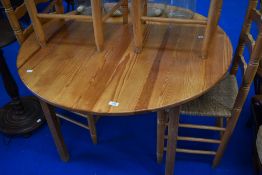 A vintage pine circular kitchen table and four ladderback chairs having seagrass type seats
