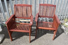 A pair of teak garden armchairs