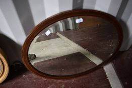 An Edwardian mahogany and inlaid oval wall mirror