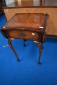 A reproduction walnut drop leaf side table, having a quarter-veneered and cross banded top with