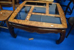 An Oriental coffee table having smoked glass panels to top, approx. 97 x 97cm