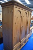 A modern pine triple wardrobe having drawer base, approx H199cm W160cm D62cm, please note back