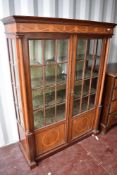 A late 19th or early 20th Century mahogany display cabinet having inlaid freeze and column supports,