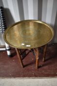An eastern brass tray top table with stained frame folding stand