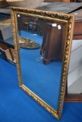 A large gilt frame over mantel or similar mirror