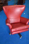 A vintage revolving easy chair having red vinyl upholstery