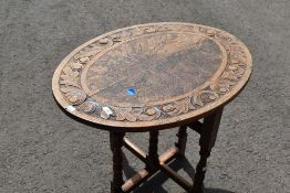 An Arts and Crafts style folding occasional table having carved oval top