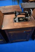 A late 19th or early 20th Century sewing machine by Vickers with integral oak cabinet