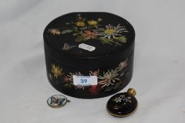 An antique lacquered box of circular form having floral painted decoration, two gold tone stick