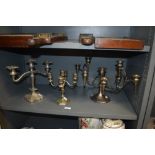 Three silver plated candlesticks, the largest measuring 25cm tall and 46cm across.