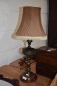 An early 20th century brass table lamp, having swag decoration and knopped stem, sat on wooden