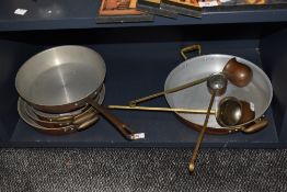 An assorted collection of vintage copper and stainless steel graduating and other pans, plus ladles