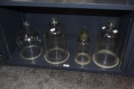 A group of four glass bell jars, of varying styles and sizes, the largest measuring 32cm tall