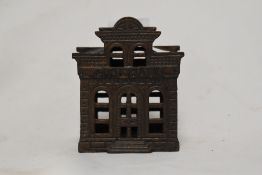 A novelty cast iron money box, in the form of a city bank, measuring 11cm tall