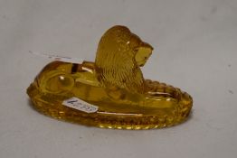 A late 19th Century moulded amber glass paperweight, in the form of a recumbent lion, 12cm long